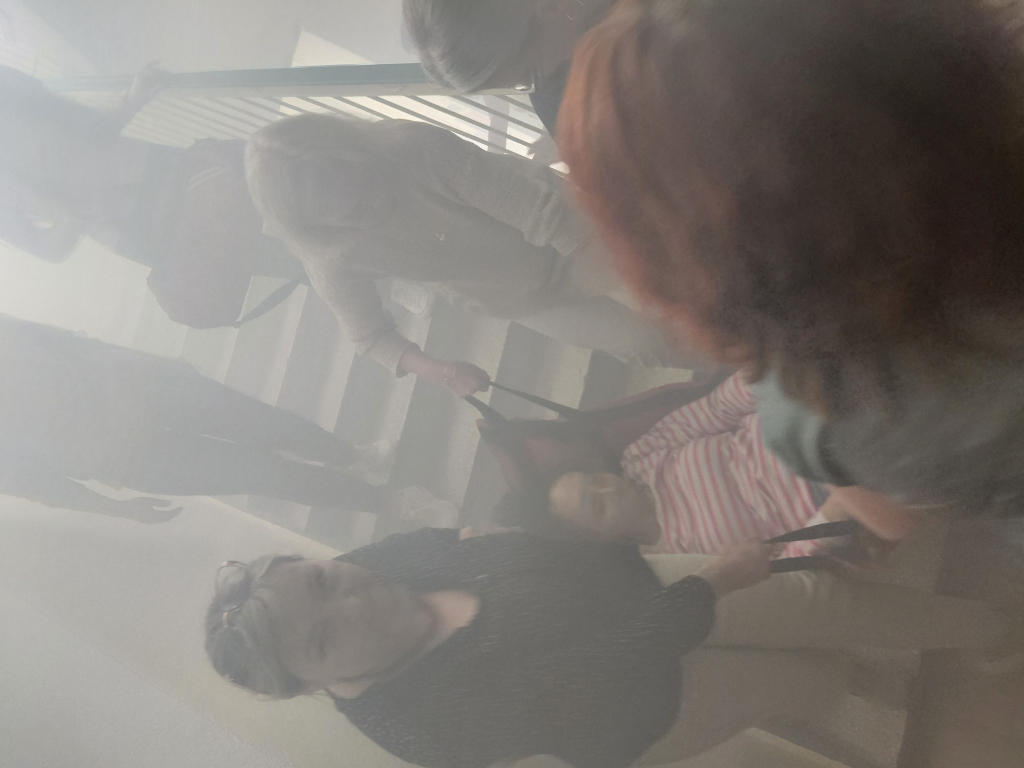 Szkolenie Bezpieczna Ewakuacja organizowane przez BON UWM, na zdjęciu zadymiona klatka schodowa, na której osoby schodzą z klatki schodowej trzymając nosze z osoba na niej leżącą. 