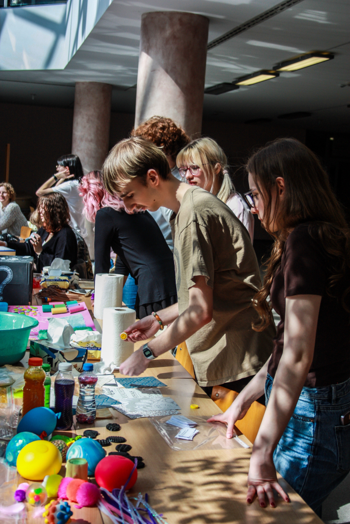 Warsztaty sensoryczne 2026 zdjęcie przedstawia stoły warsztatowe z różnymi kolorowymi akcesoriami jak farby, gniotki, papier i inne